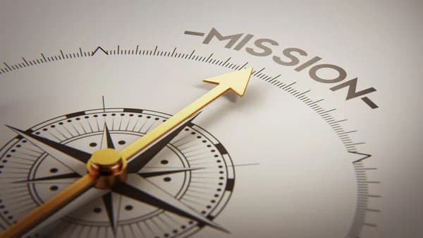 A wooden dart hitting the center of a target with the word Mission on it.